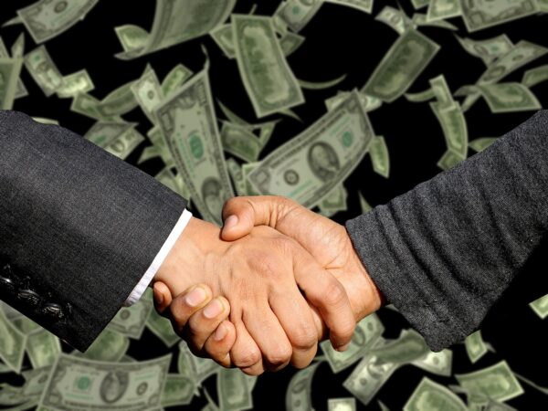 handshake over dollar bills