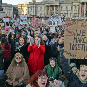 large group od women in close formation in forground hand made placard with 'We march together'in centre - round outside black, tarns. muslim, poor, lgbtiq, disabled, migrant