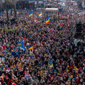 Large crowd photographed from air so individuals are bit clear but a few flags are visible