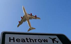 Plane against blue sky with a sign saying Heathrow in bottom part of panel