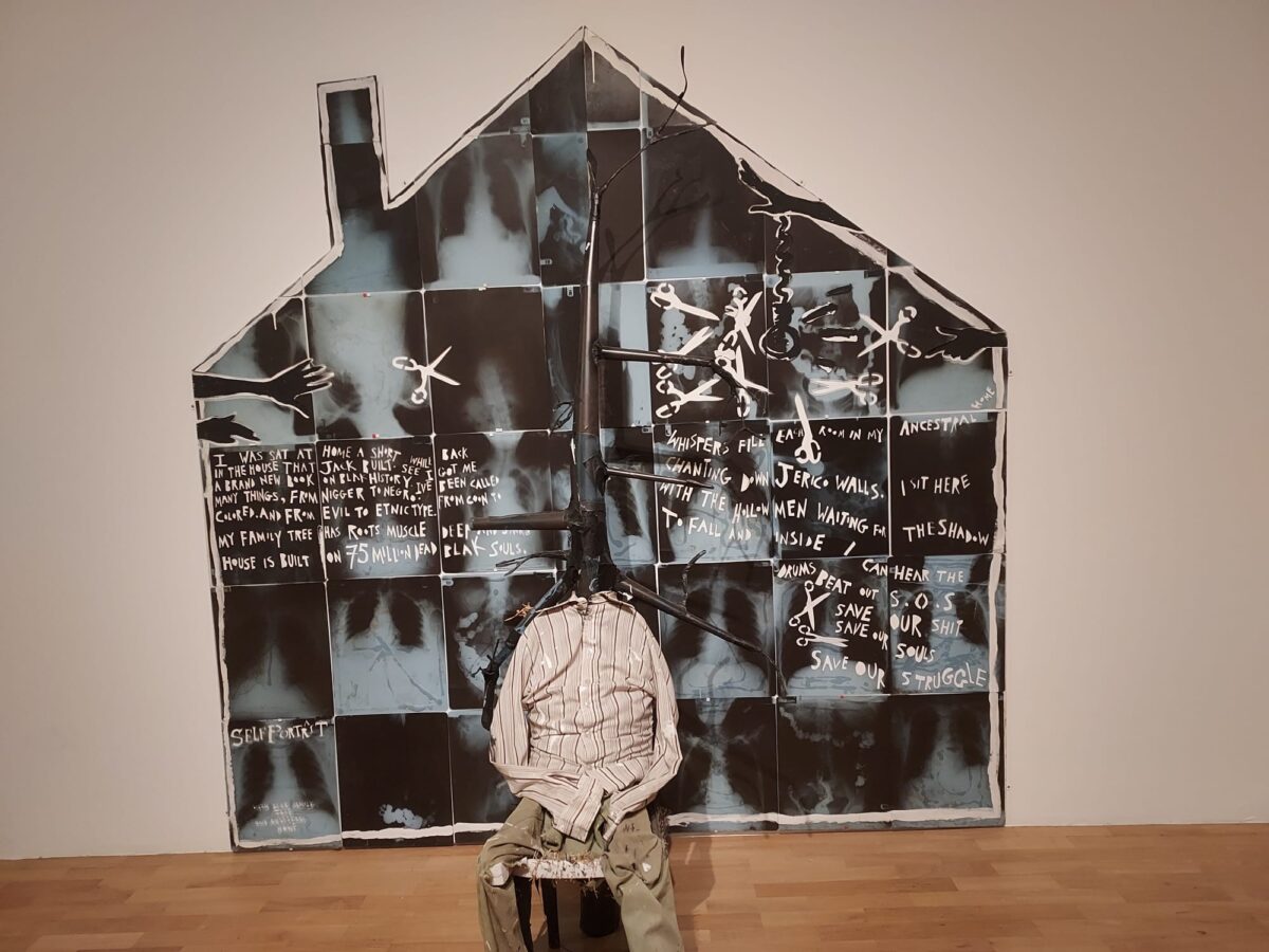 Donald Rodney artwork. A Person with a tree coming out of head sitting in front of a house made up up x rays with text describing the black experience