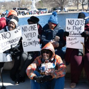 Group of African Americans in warm clothing with handmade signs, slogans include ' No one voted for Elon Musk' and '