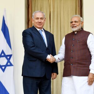 Netayahu and Modi shake hands beside their respective flags