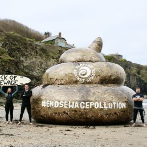 surfers against sewage prottest on beach with giant turd