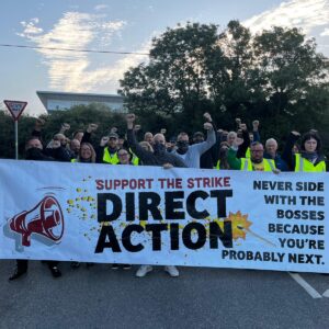 Banner reading: Support the strike then Direct Action in large type and Never side with the bosses, you are probably next held by large group of people. Photo: Mike Tucker