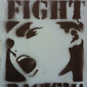 Graffiti that says "fight racism" with an image of a person shouting.