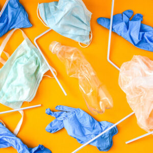 Floppy masks, shields and disposible glove aggainst orange background.
