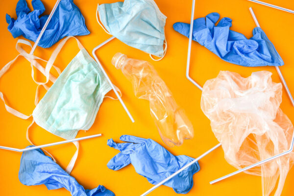 Floppy masks, shields and disposible glove aggainst orange background.
