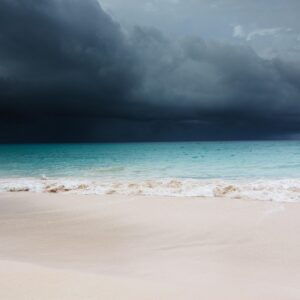 A storm approaches a white sand beach