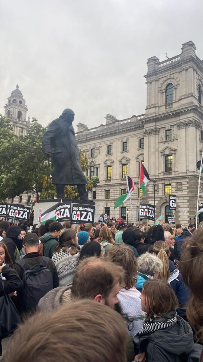 Crowd in Palriament Squarre mainly with their backs to us and many signs saying Stop Starving Gaza