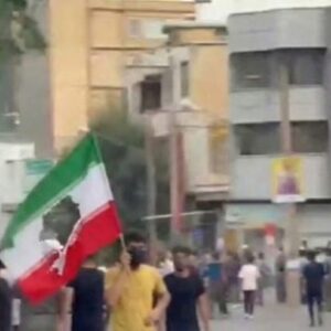 Protesters waving the flag of Iran with the national Islamic emblem, a stylised representation of the word Allah, cut out