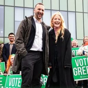 Hannah Spencer and Zack Polansky in front of a crowd holding "Vote Green" placards.