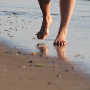 Feet tread on wet sand at a beach.