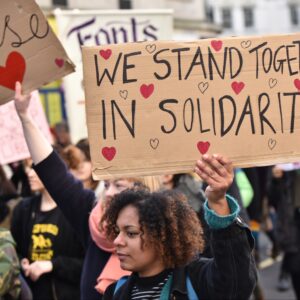 Large hand made placrd: We srand together in solidarity