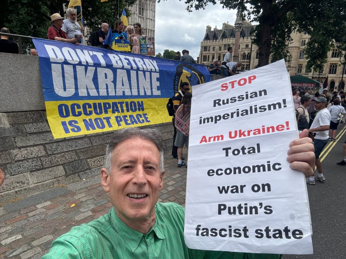 Large blue and yellow banner Dont betray Ukraine: Occupation is not peace in background handmade placard in foreground: Stop Russian imperialism Arm Ukraine Total economic war on Putins fascist state