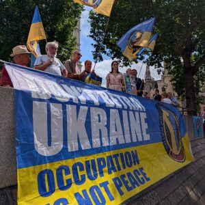 Large blue and yellow banner Dont betray Ukraine: Occupation is not peace surrounded by Ukranian flags