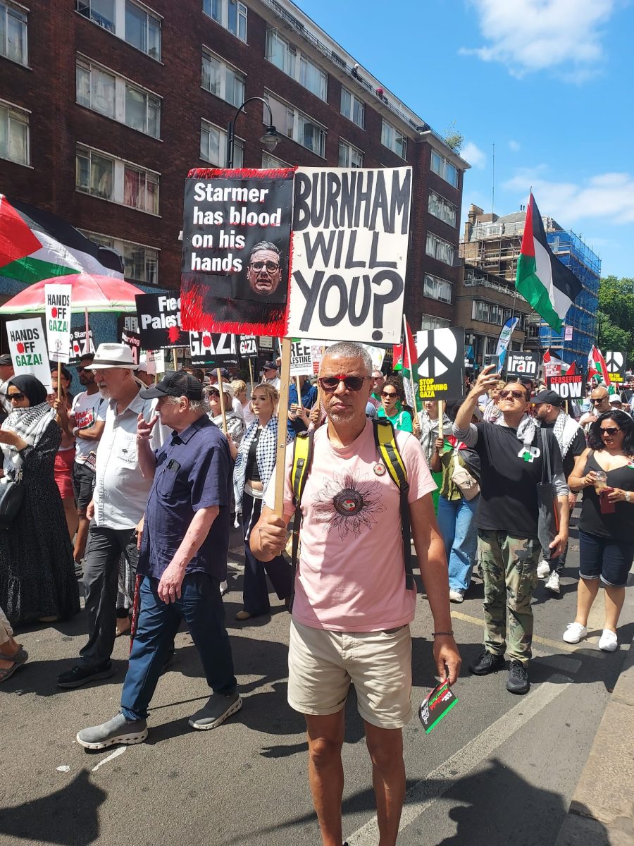 palestine demonstrator with poster referencing Burnham reading Starmer has blood on his hands - Brunham will you?