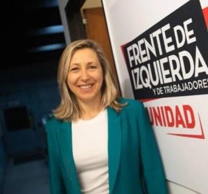 Myriam Bregman stands in front of a banner that reads "Frente de Izquierda y de trabajadores - Unidad"