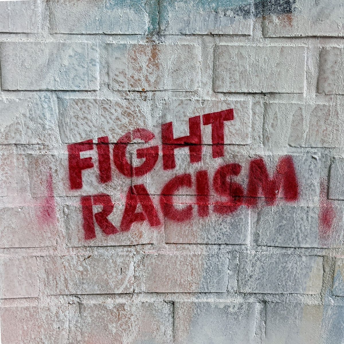 Stencilled letters in red 'Fight Racism' on greyish wall Adrian, pexels