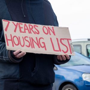 shutterstock image of man holding sign saying 7 yeas on housing list