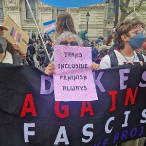 Protesting ehrc guidelines - poster in pink reads trans inclusive feminism always against banner reading dykes v facism. Photo: Echo Fortune